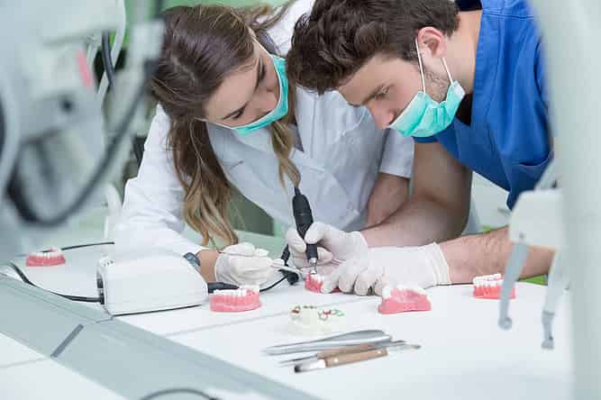 Two dental students work on dentures in lab