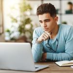 Pensive man using laptop at home