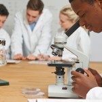Male Pupil Using Microscope In Science Class