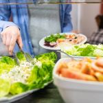 Stock photo of the hand of a man getting salad at a self-service. Lifestyle