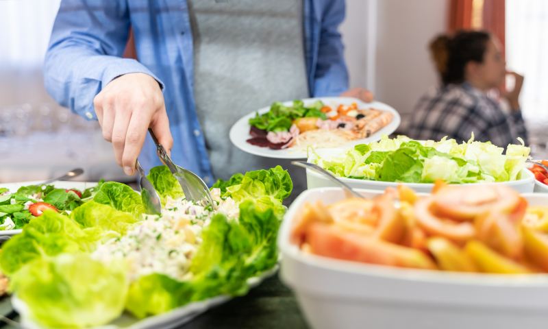 Stock photo of the hand of a man getting salad at a self-service. Lifestyle
