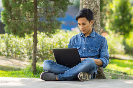 Asian young  man using computer outdoor