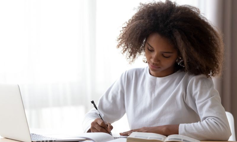 Young girl writing her princeton supplement essays on notebook