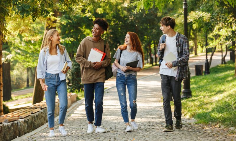 Group of happy students walking at the campus outdoors