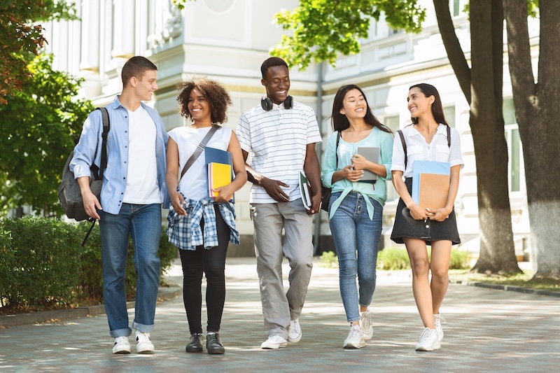 Five students walking together on a college campus