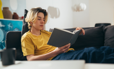 teen boy reading book at home