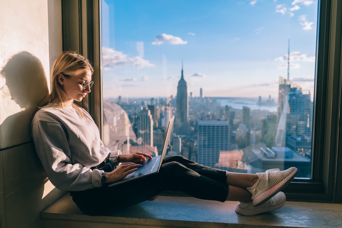 Female student typing on laptop overlooking New York City skyline