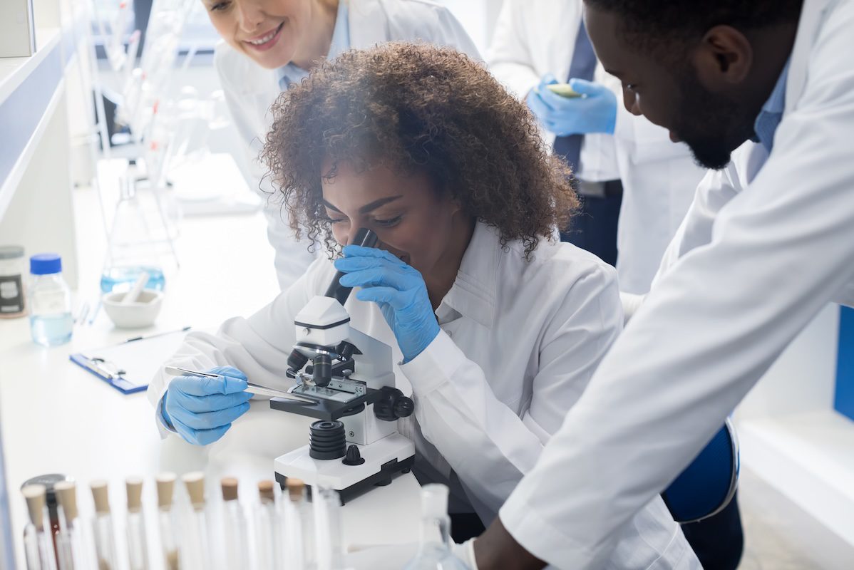 High school student looks in a microscope during a summer internship