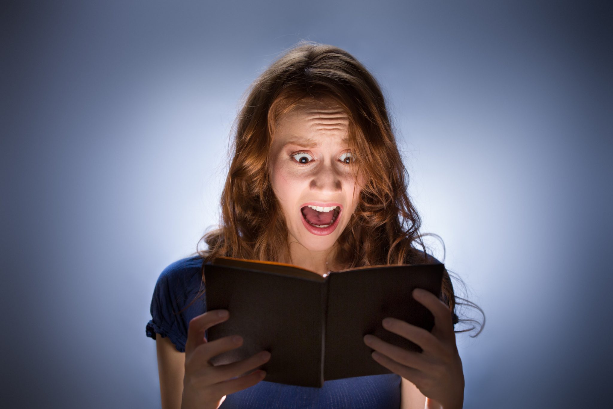 young woman reading a book and screaming