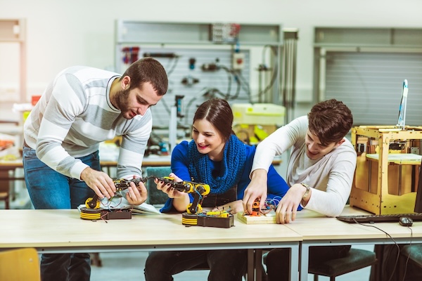Young students of robotics preparing robot for testing in workshop