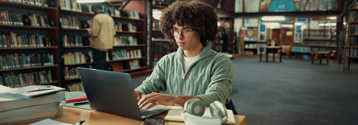 Student studying with laptop, focused on academic success and college preparation.
