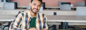 Smiling graduate student works in a university computer lab.