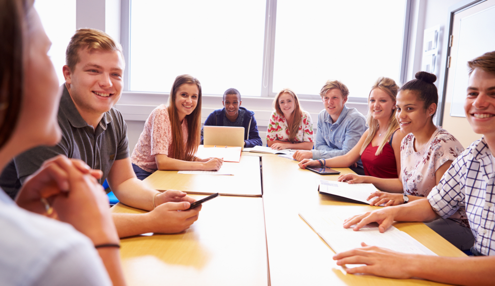 Group Of Students Sitting At Table Having Discussion