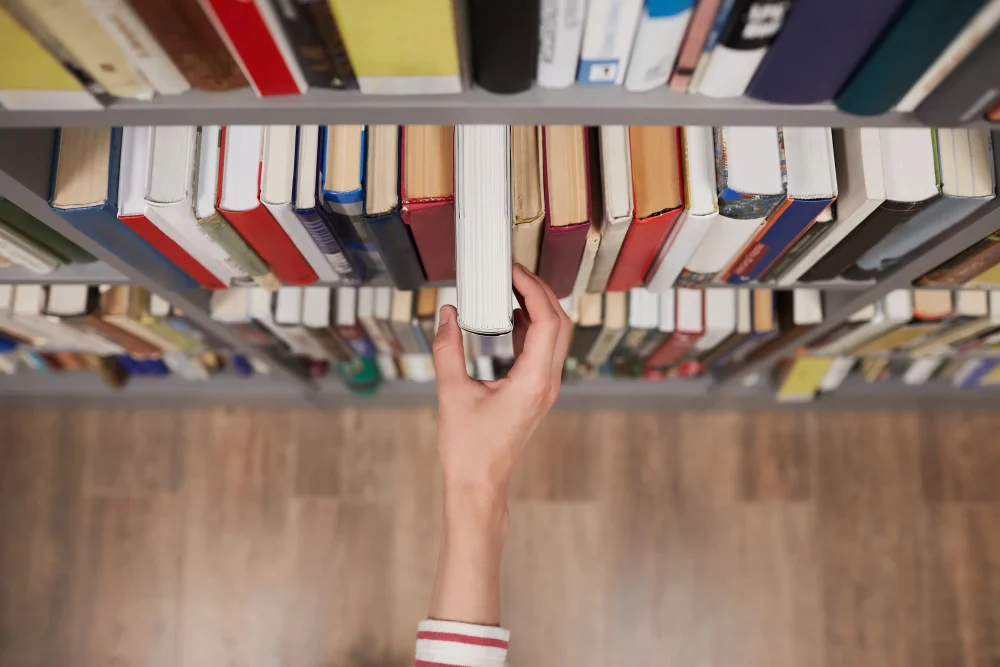 hand reaching for a book on library shelf