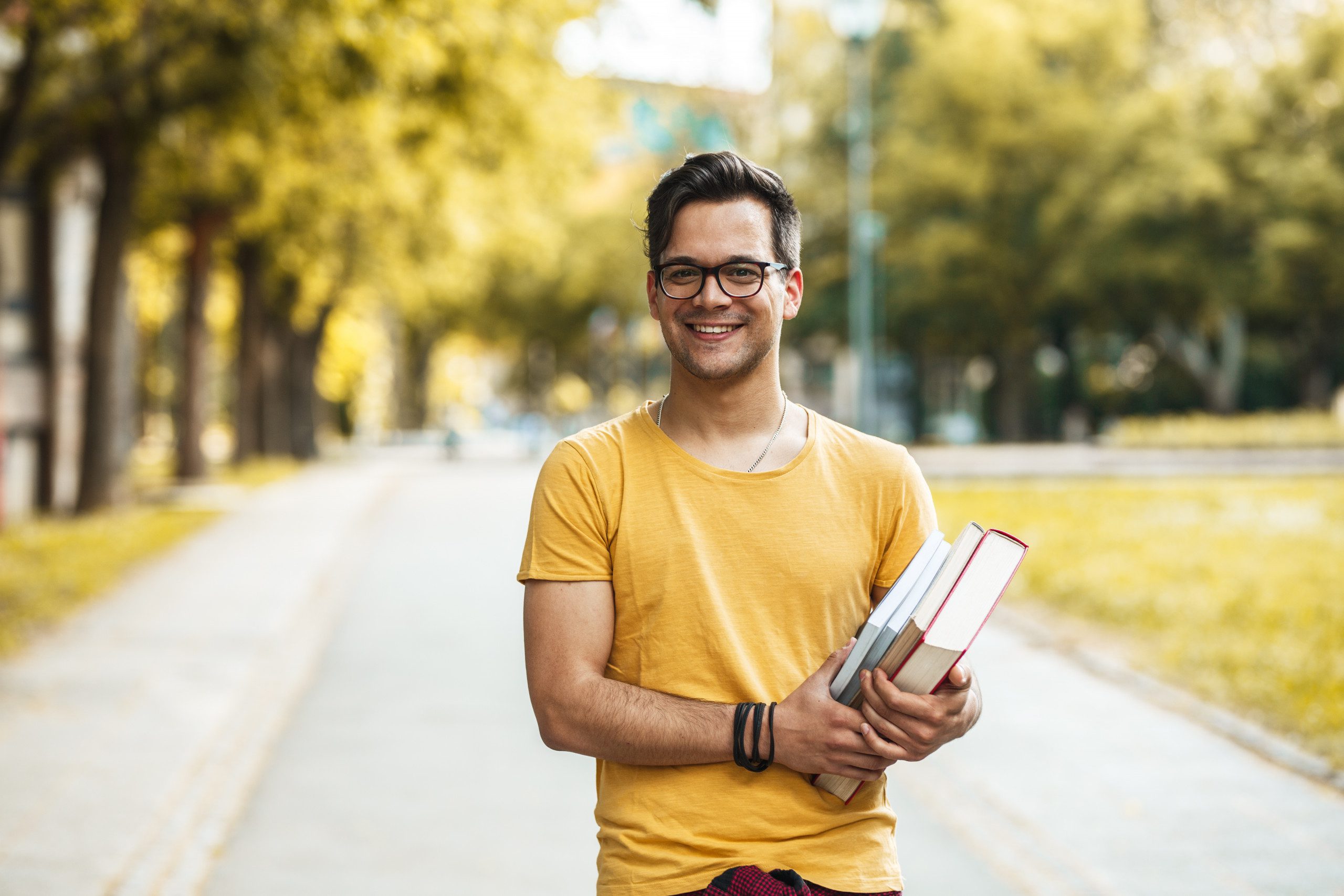 Male student with books standing on college campus