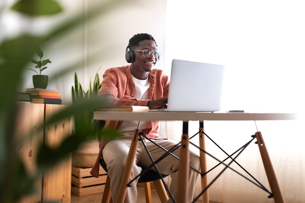 smiling student with headphones on laptop