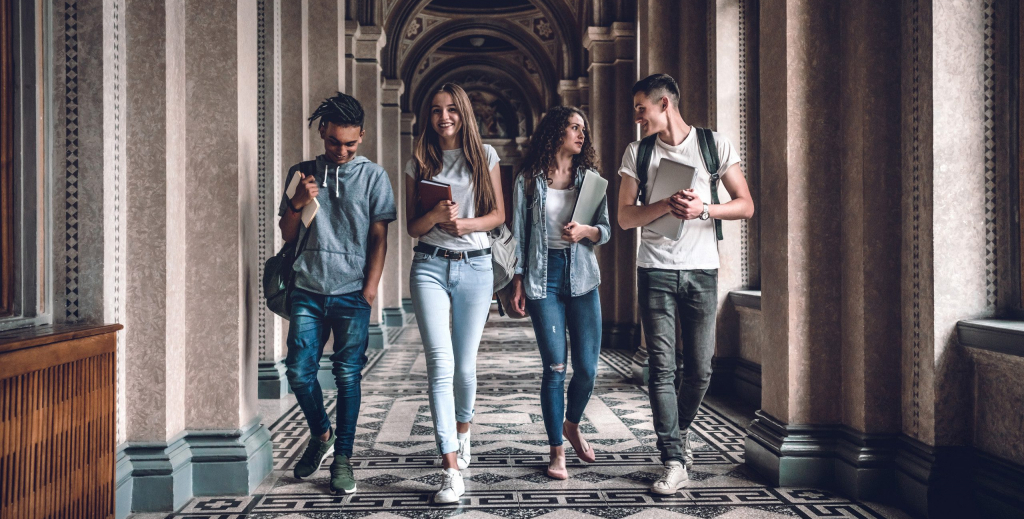 Four students walking in the halls of a college building