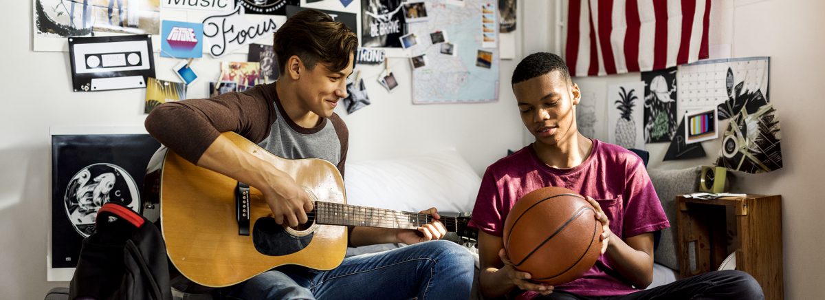 Teenage boys hanging out in a bedroom music and sports hobby concept