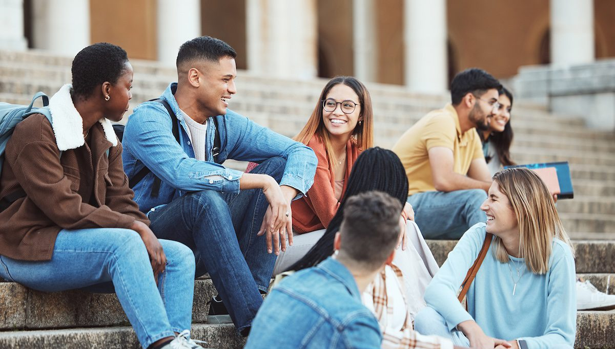 Laughing students sitting on university campus stairs