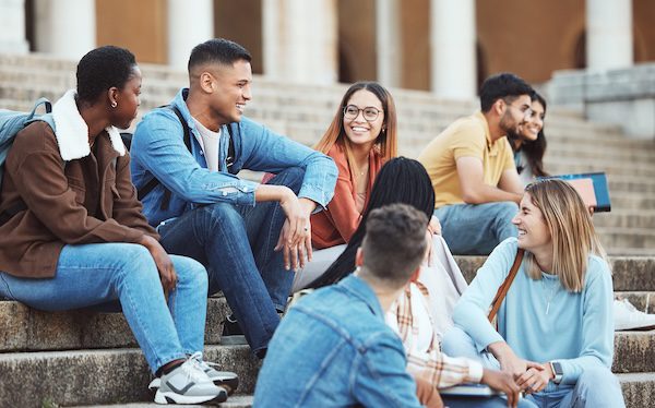 Laughing students sitting on university campus stairs